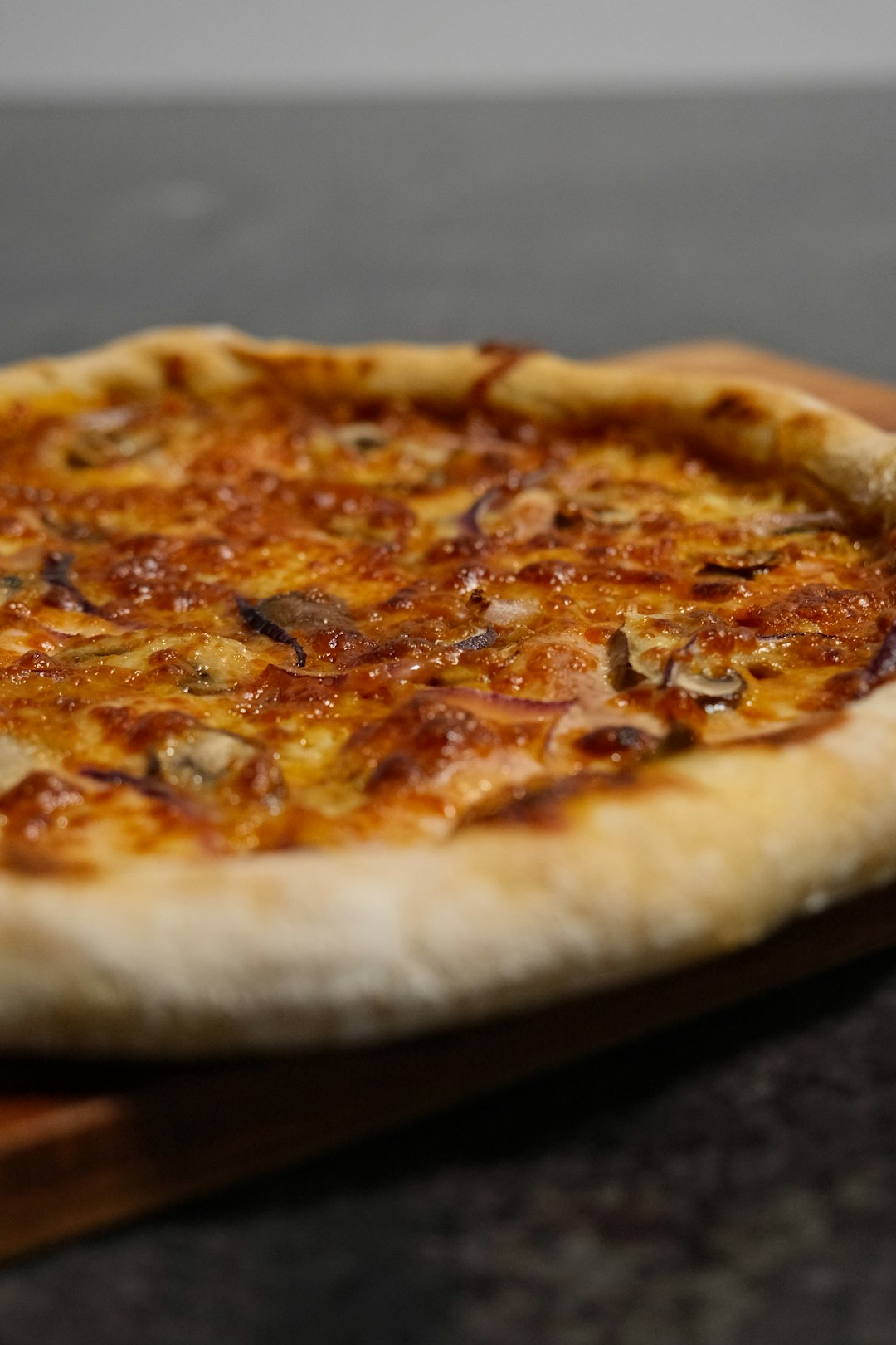 Cooked pizza on a cutting board, seen from the side.