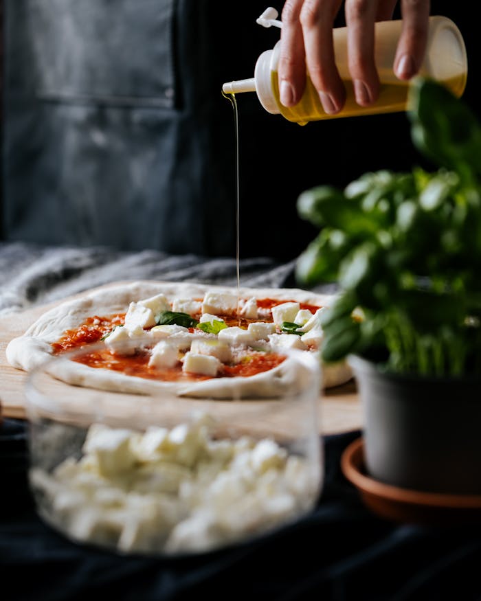 Close-up of artisan pizza with fresh ingredients and olive oil drizzle, featuring basil and cheese.